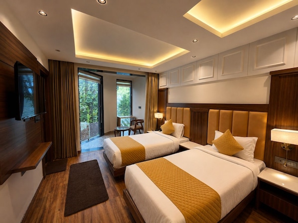 A hotel room with two beds, a TV, a desk, and a balcony with curtains. - SSH Ardmore Hills (Mussoorie)