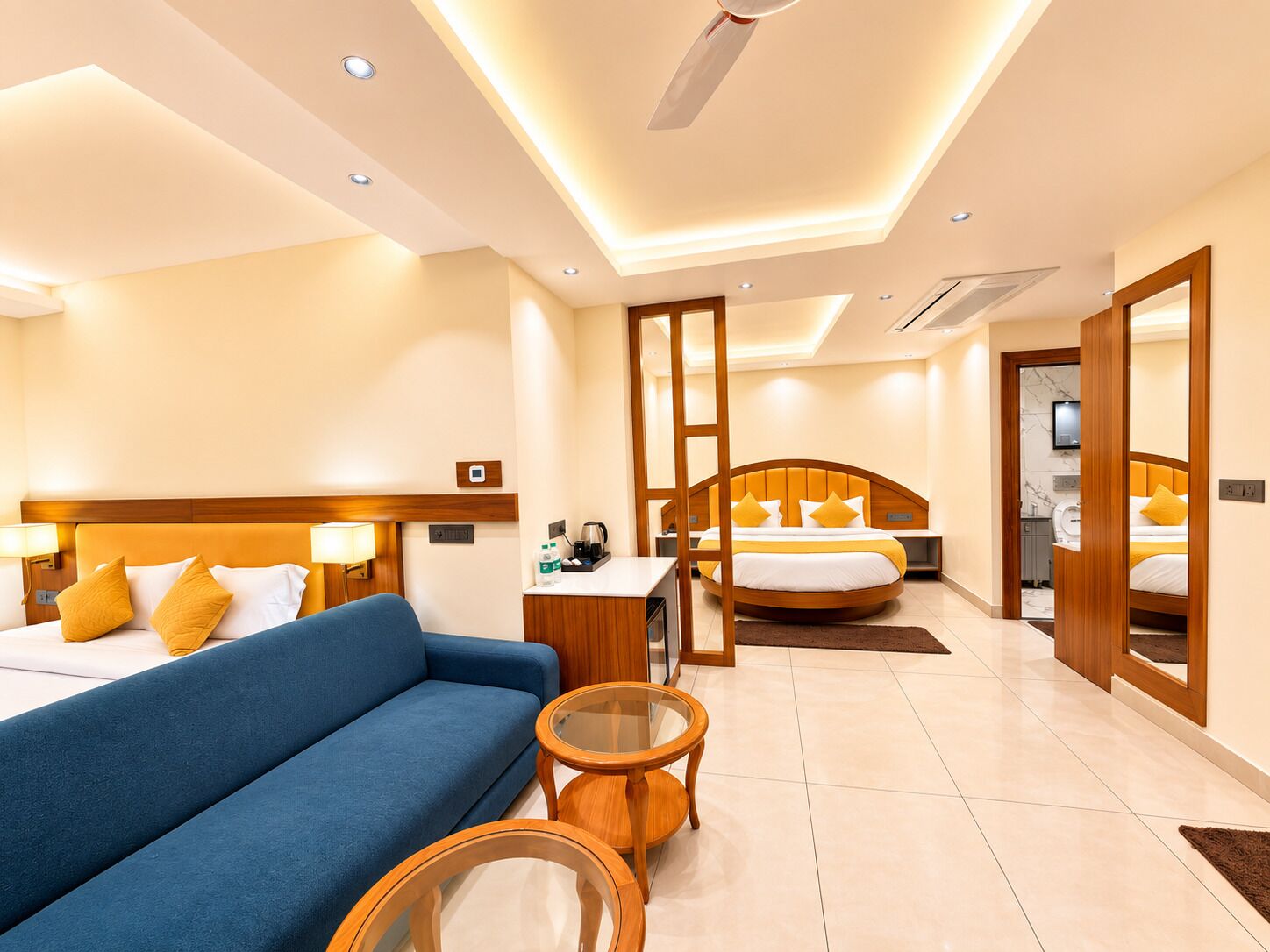 A hotel room with a bed, a sofa, a desk, and a mirror.