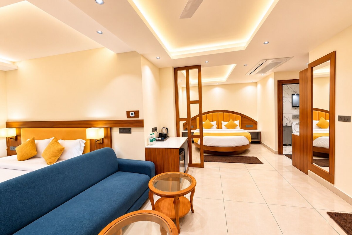 A hotel room with a bed, a sofa, a desk, and a mirror.