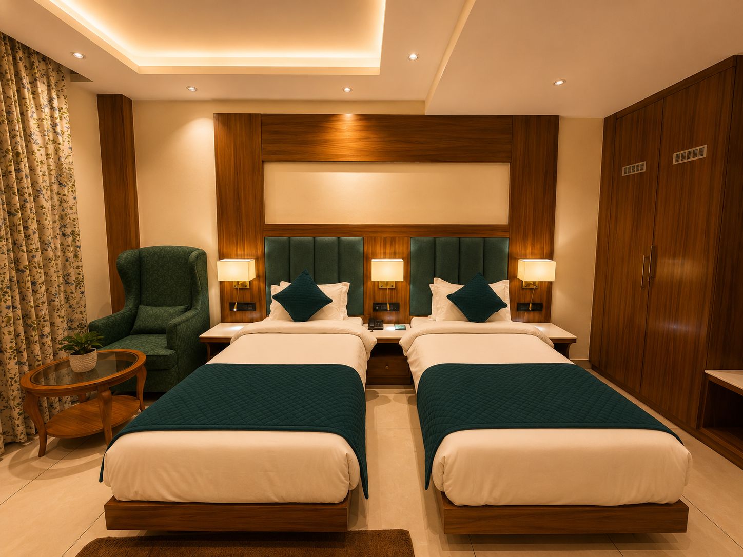 A hotel room with two beds, a green armchair, a small table, and a wardrobe.