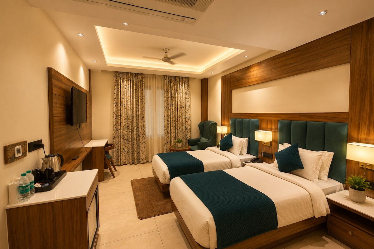 A hotel room with two beds, a desk, a television, and a ceiling fan.