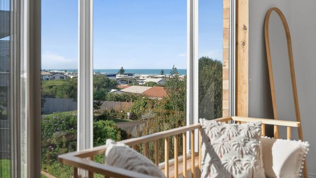 Una stanza con ampie finestre, una sedia di legno e vista su una zona costiera.