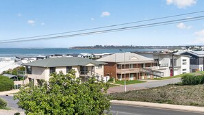 Una zona residenziale costiera con case moderne, vista libera sull'oceano e una strada con linee elettriche aeree.