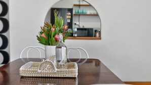 Un tavolo da pranzo con un sottotavolo intrecciato, una bottiglia di vetro e un bouquet di fiori.