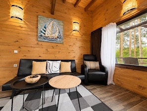 A wooden interior with a sofa, a chair, a round table, and a painting of a sailboat. - Club Paradise Bay Iskar Lake (Dolni Pasarel)