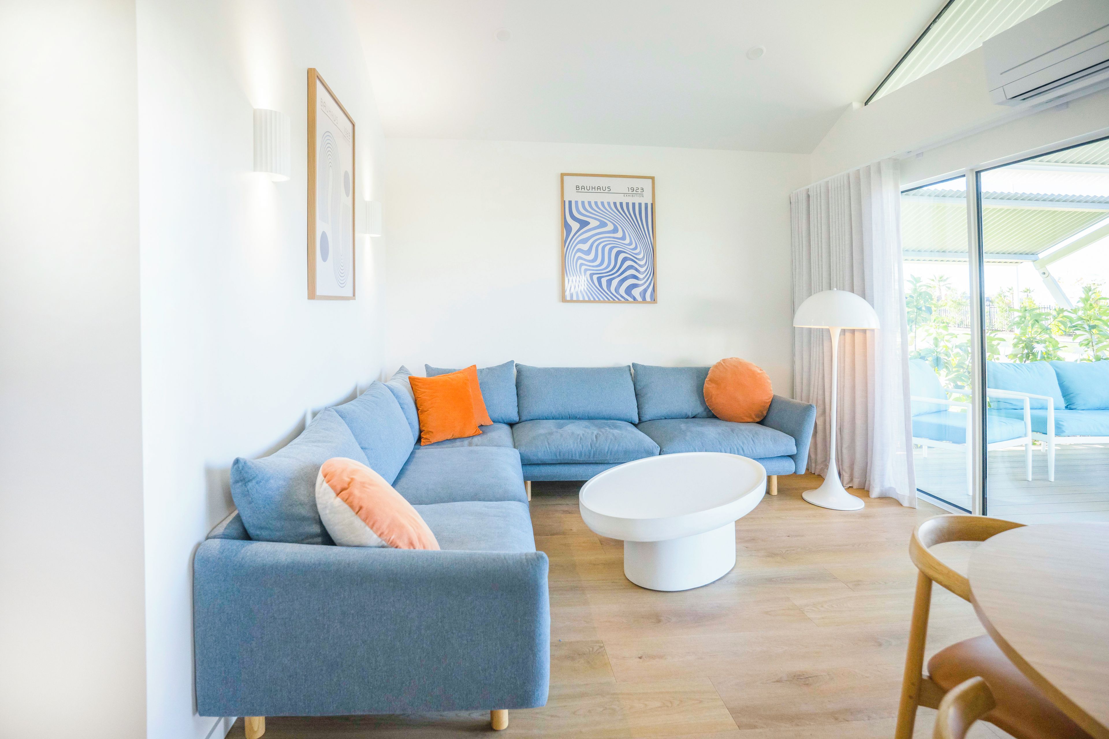 A modern living room with a sectional sofa, a coffee table, and a dining area with a table and chairs.