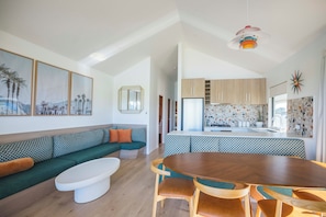 A modern living room with a sofa, coffee table, and dining area with chairs.