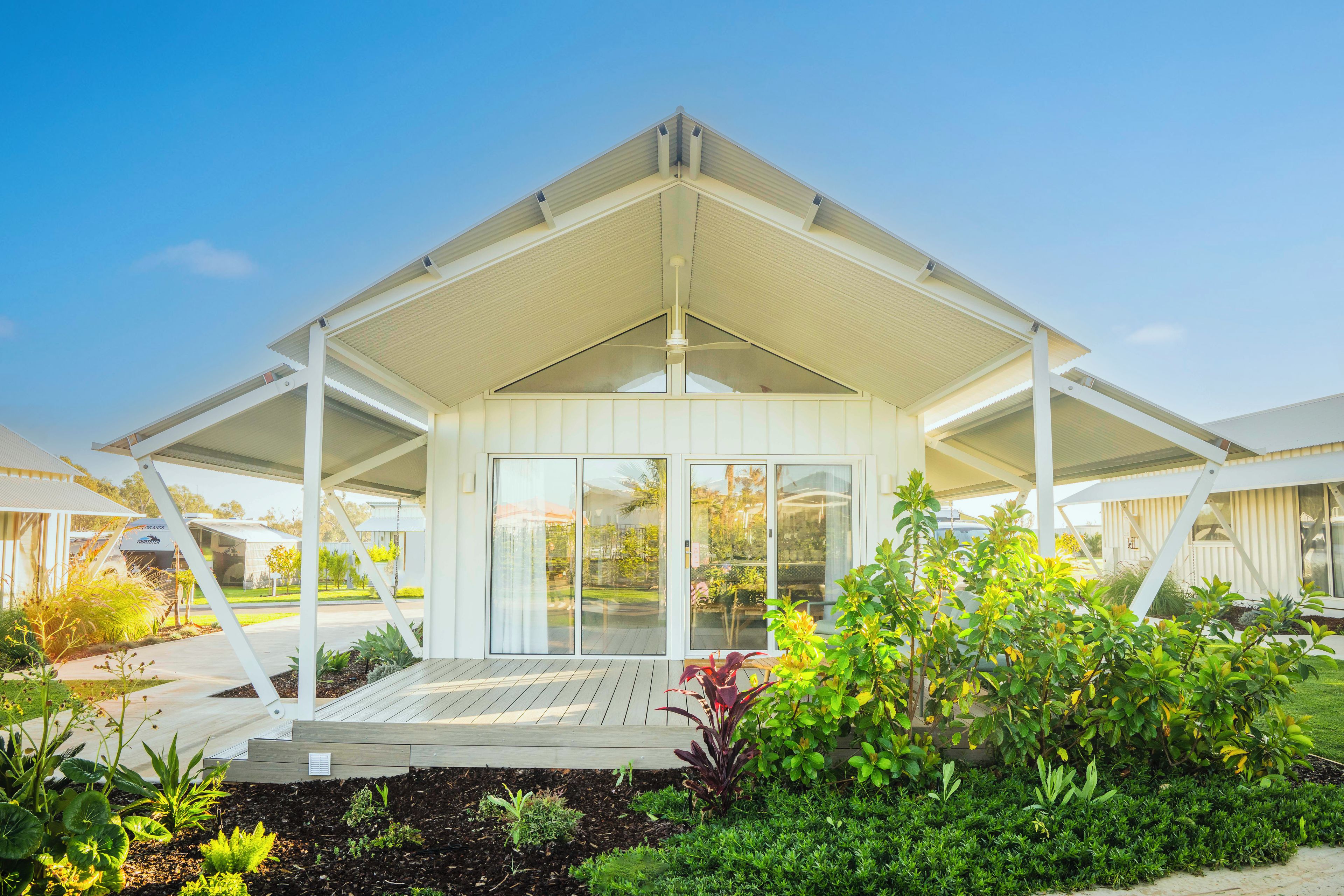 A modern, single-story building with a covered patio area, large windows, and a well-maintained garden.