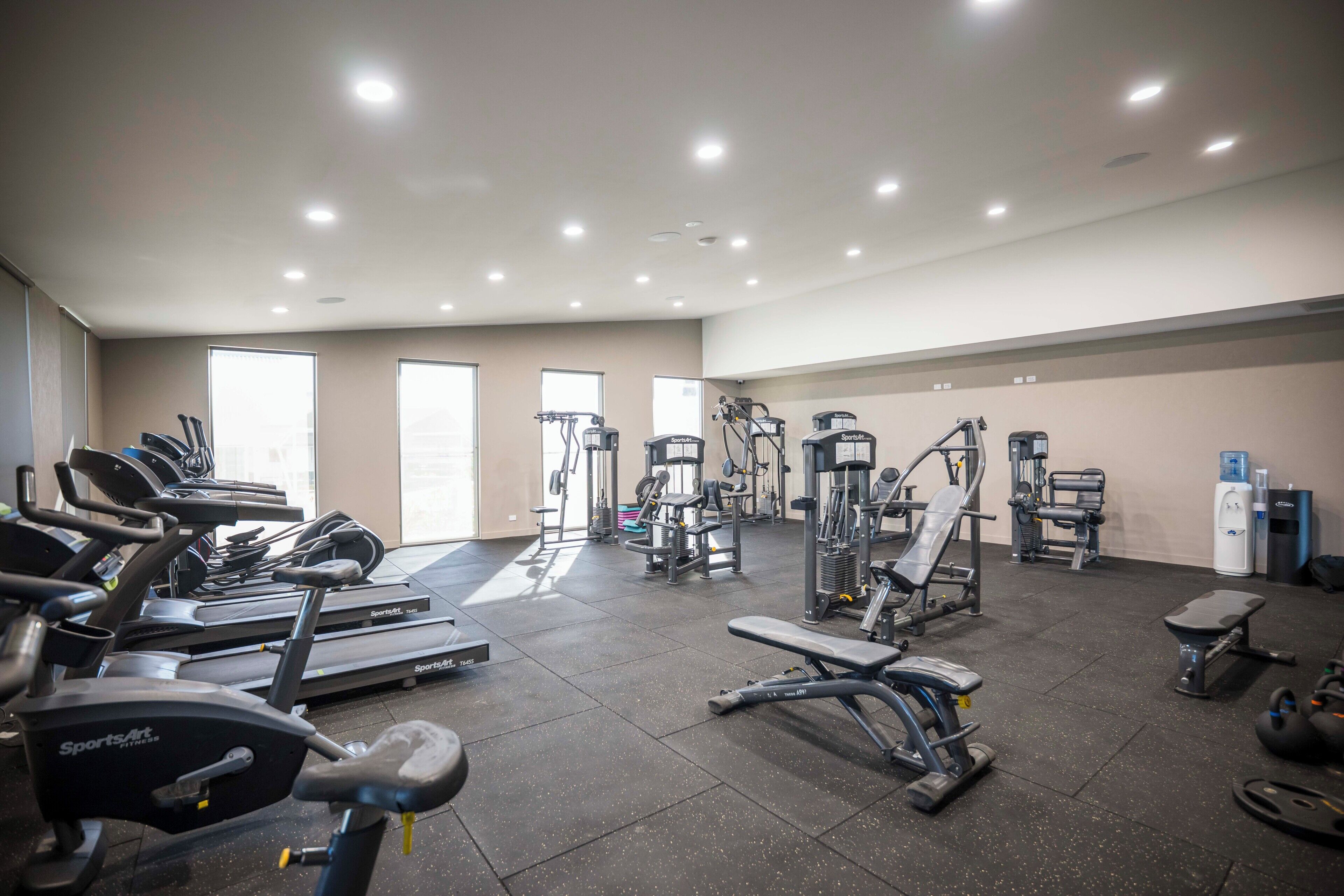 A gym with various exercise equipment, including treadmills, weight machines, and free weights.