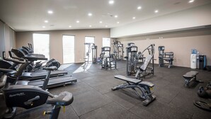 Et fitnessrum med forskellig træningsudstyr, herunder løbebånd, styrkemaskiner og håndvægte.