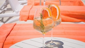 Et loungeområde ved poolen med liggestole og et bord med en drink.