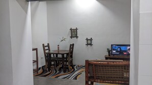 Een eetgedeelte met een tafel, stoelen, een televisie en decoratieve muurkunst.