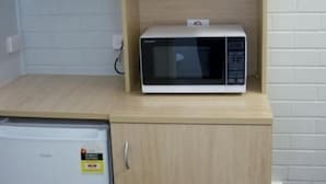 Eine kleine Küche mit Mikrowelle, Kaffeemaschine und kleinem Kühlschrank.