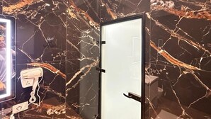 A bathroom with a marble wall, a mirror, and a hairdryer on a stand. - Liel Holiday (Vlore)