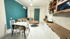 A modern kitchen with a dining area, a sofa, and a TV. - Liel Holiday (Vlore)