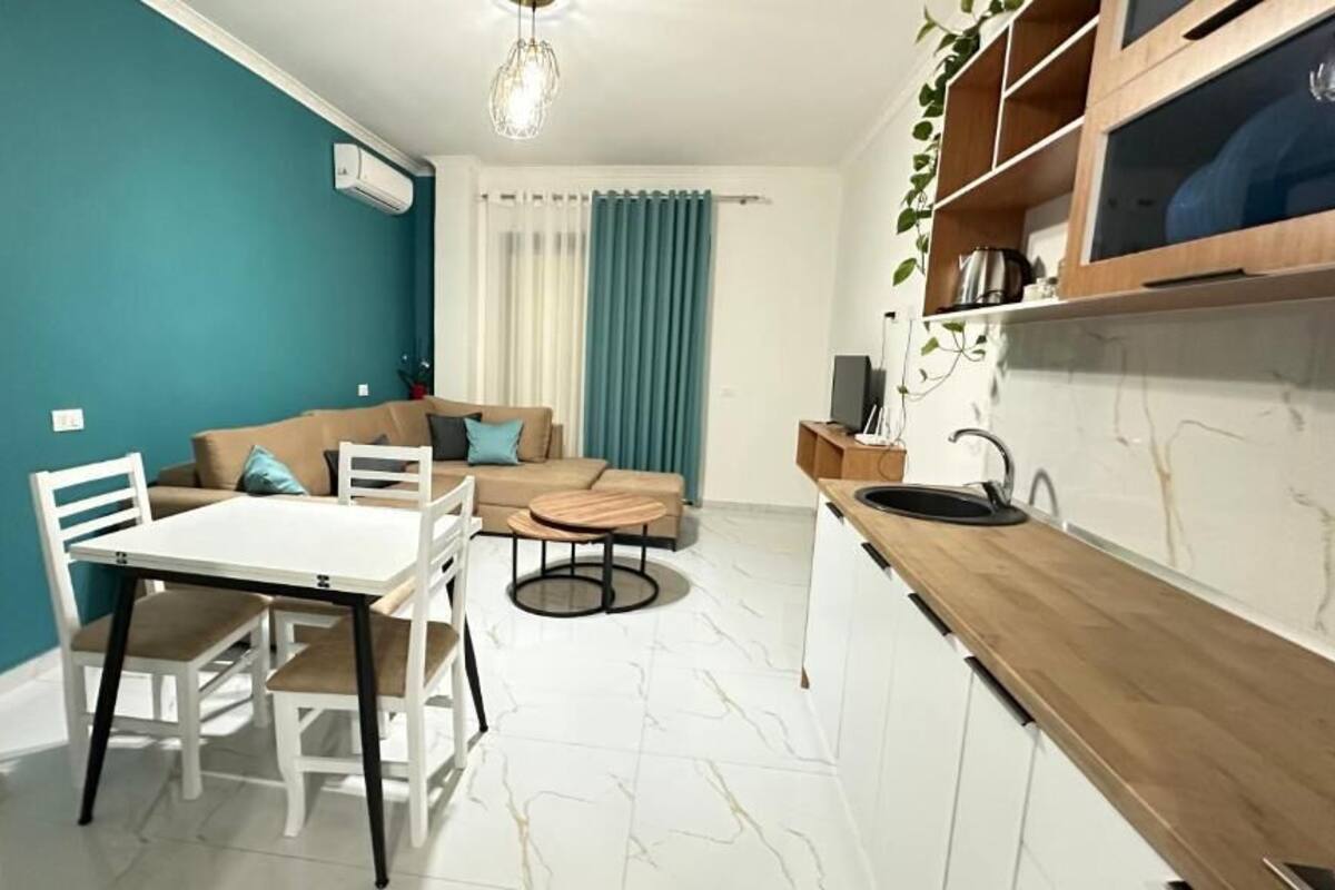A modern kitchen with a dining area, a sofa, and a TV.