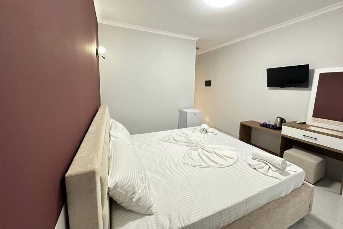 A hotel room with a bed, a desk, a television, and a bedside table.