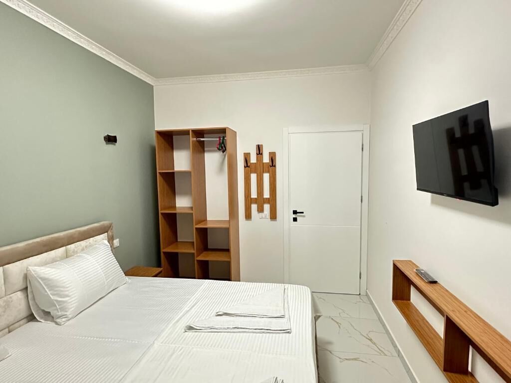 Ein Schlafzimmer mit einem Bett, einem Kleiderschrank, einem Fernseher und einer Tür.
