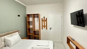 Ein Schlafzimmer mit einem Bett, einem Kleiderschrank, einem Fernseher und einer Tür.