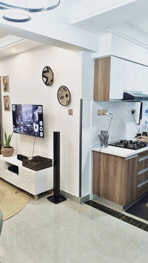 Une cuisine moderne dotée d’une cuisinière intégrée, d’un téléviseur à écran plat et d’œuvres d’art décoratives murales.