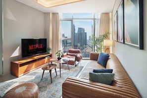 A modern living room with a large TV, leather sofa, and a view of the cityscape through large windows. - Chic 2BR in Paramount Midtown  (Dubai)