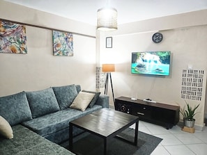 Ein Wohnzimmer mit Sofa, Couchtisch, Fernseher und Wandkunst.