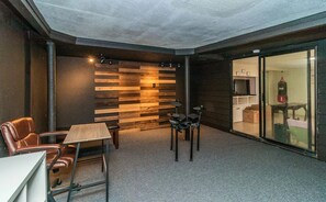 A room with a wooden slat wall, a table with chairs, a punching bag, and a sliding glass door leading to another room.
