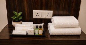 Ein Badezimmer im Hotel mit einem Holzbidet, einer Topfpflanze, einem Tablett mit Pflegeprodukten und einem Handtuch.