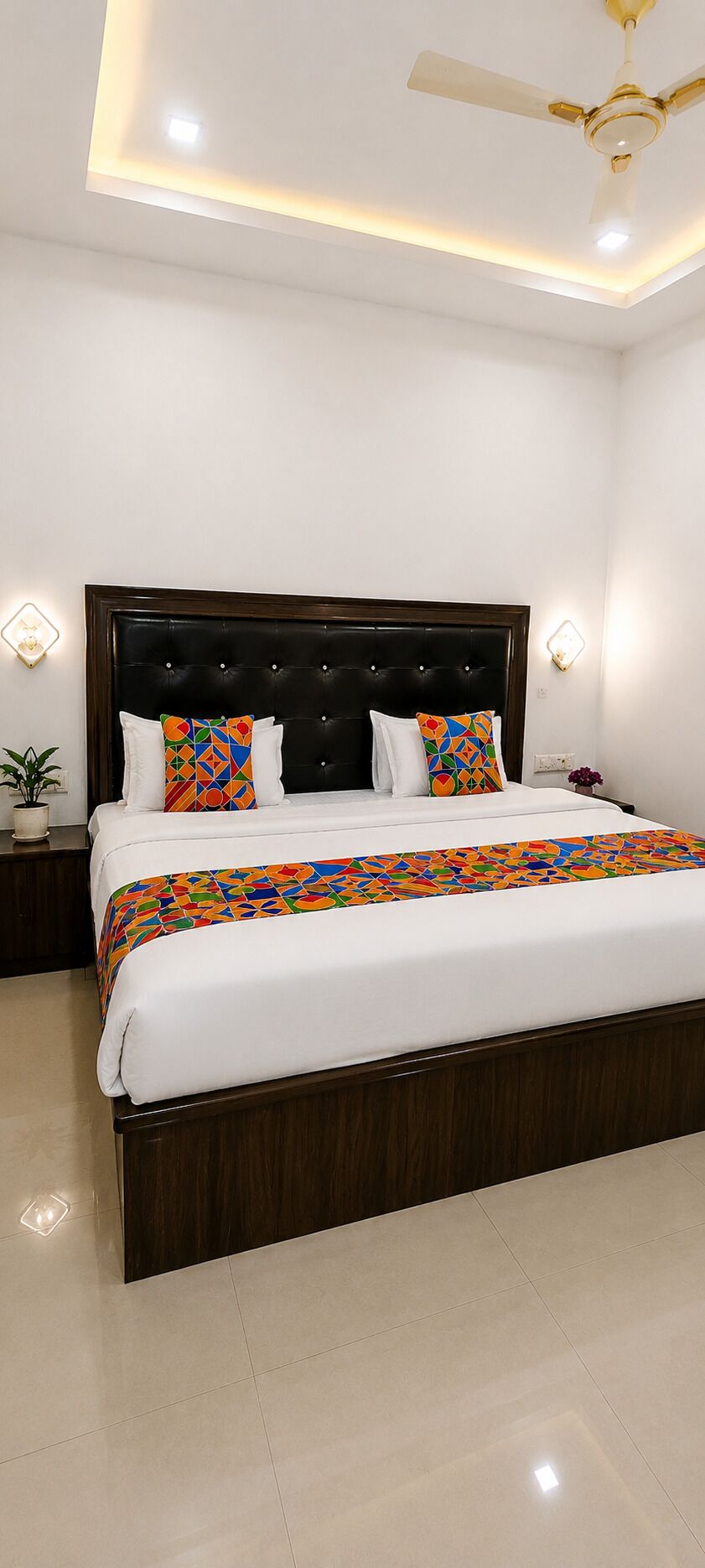A modern bedroom with a large bed, a ceiling fan, and wall-mounted lighting.