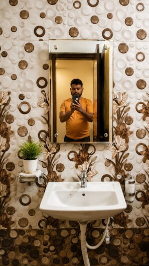 Ein Badezimmer mit einem weißen Waschbecken, einem Spiegel und einer Wand mit kreisförmigen Mustern.