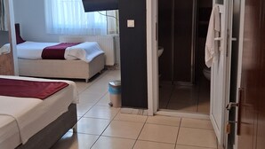 A hotel room with a bed, a TV, a bathroom, and a door leading to another room.
