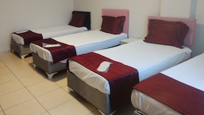 A hotel room with three single beds, each with a red headboard and white bedding.