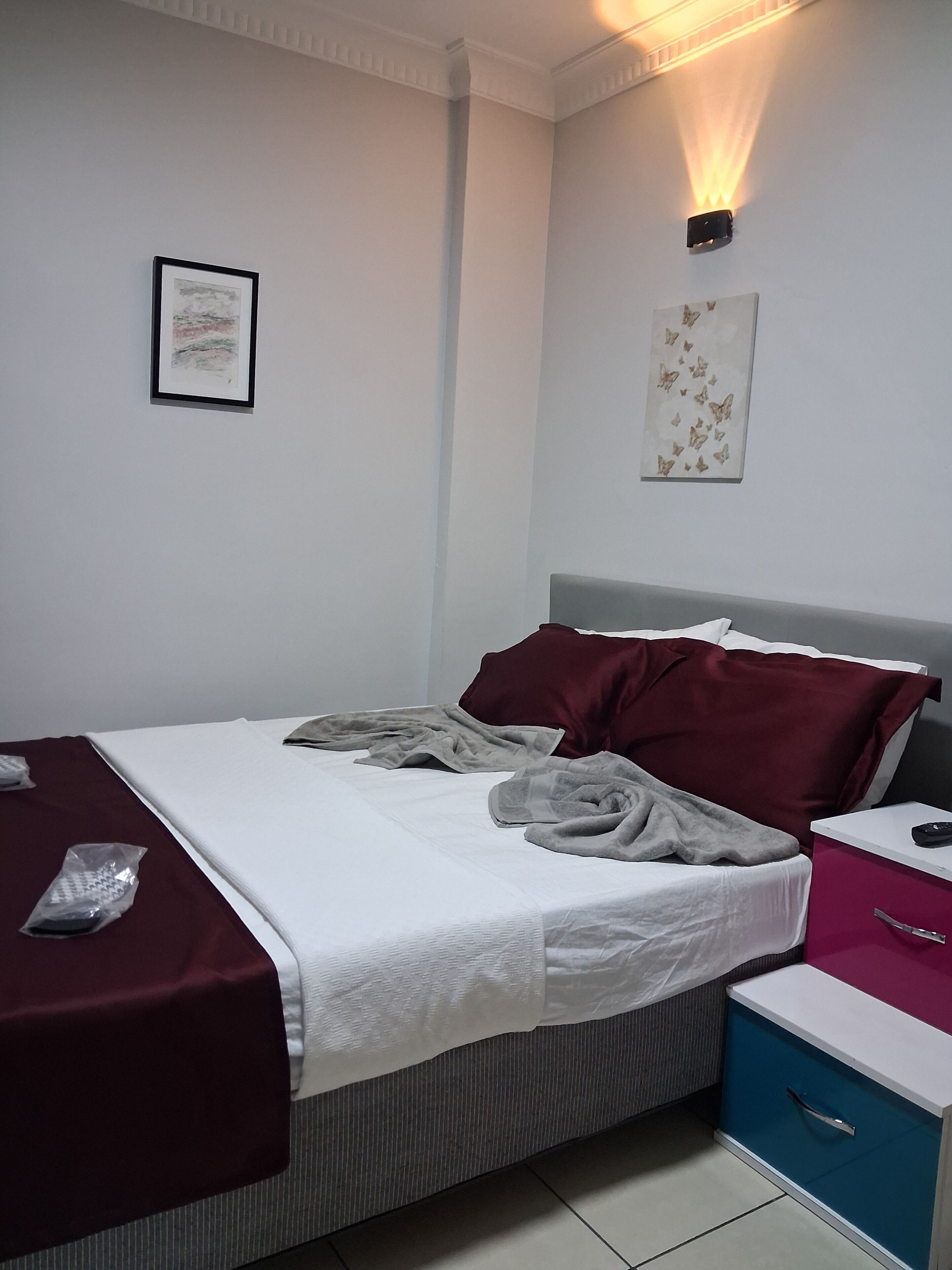 A neatly made bed with pillows, a bedside table with a lamp, and a wall-mounted artwork.