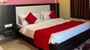 Habitación de hotel con una cama grande, ventilador de techo, mesita de noche y toma de corriente.