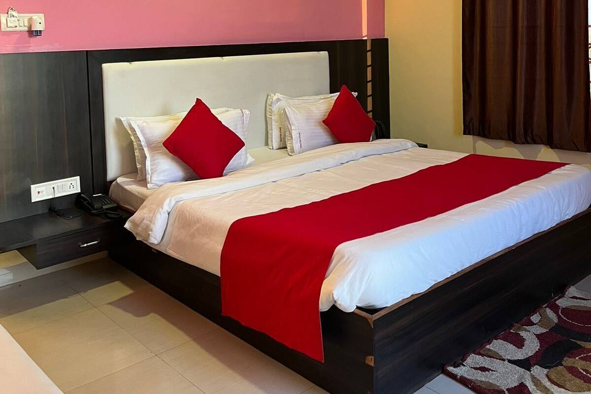 Une chambre d’hôtel avec un grand lit, un ventilateur de plafond, une table de chevet et une prise de courant.