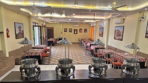 Un comedor con varias mesas, estaciones de buffet y ventiladores de techo.