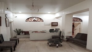 A reception area with a desk, chairs, a sofa, and a decorative wall piece. - SAH HAVELI 400m WALK TO KASHI VISHWANATH (Varanasi)