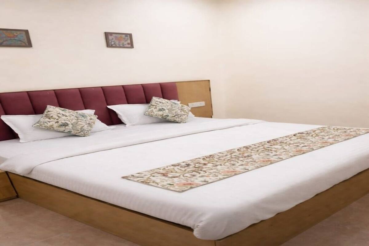 Ein Bett mit Holzrahmen, weißer Bettwäsche und einer blumigen Tagesdecke.
