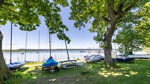 A lakeside area with boats docked and a tree providing shade.