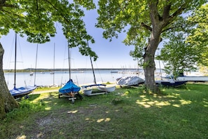 A lakeside area with boats docked and a tree providing shade. - Apartment 'Hof am Ammersee' with Lake View, Balcony, and Wi-Fi (Pähl)
