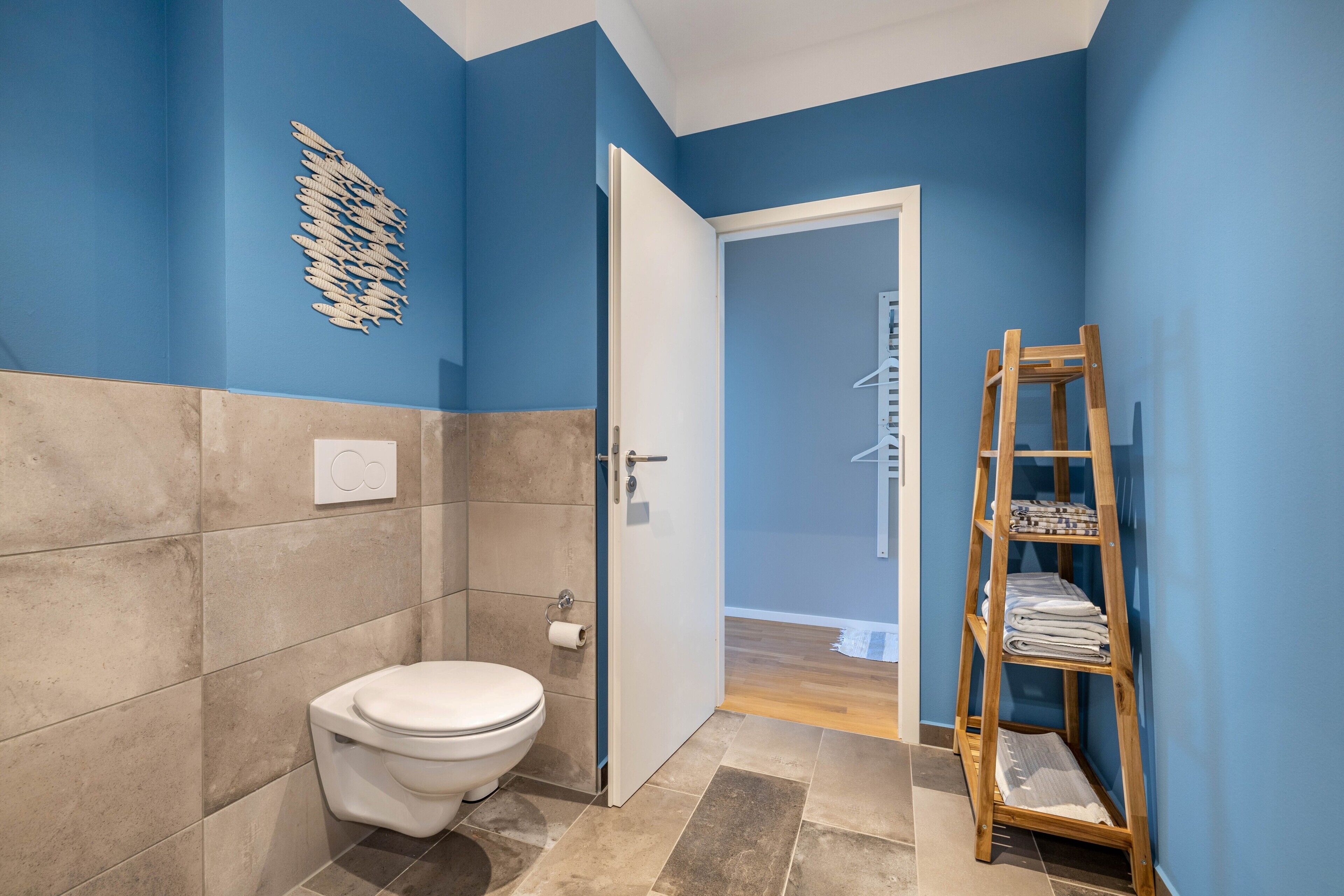 Un bagno con il water, un portascopevoli e una scala in legno.