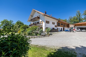 A two-story house with a balcony, a garage, and a gravel driveway.