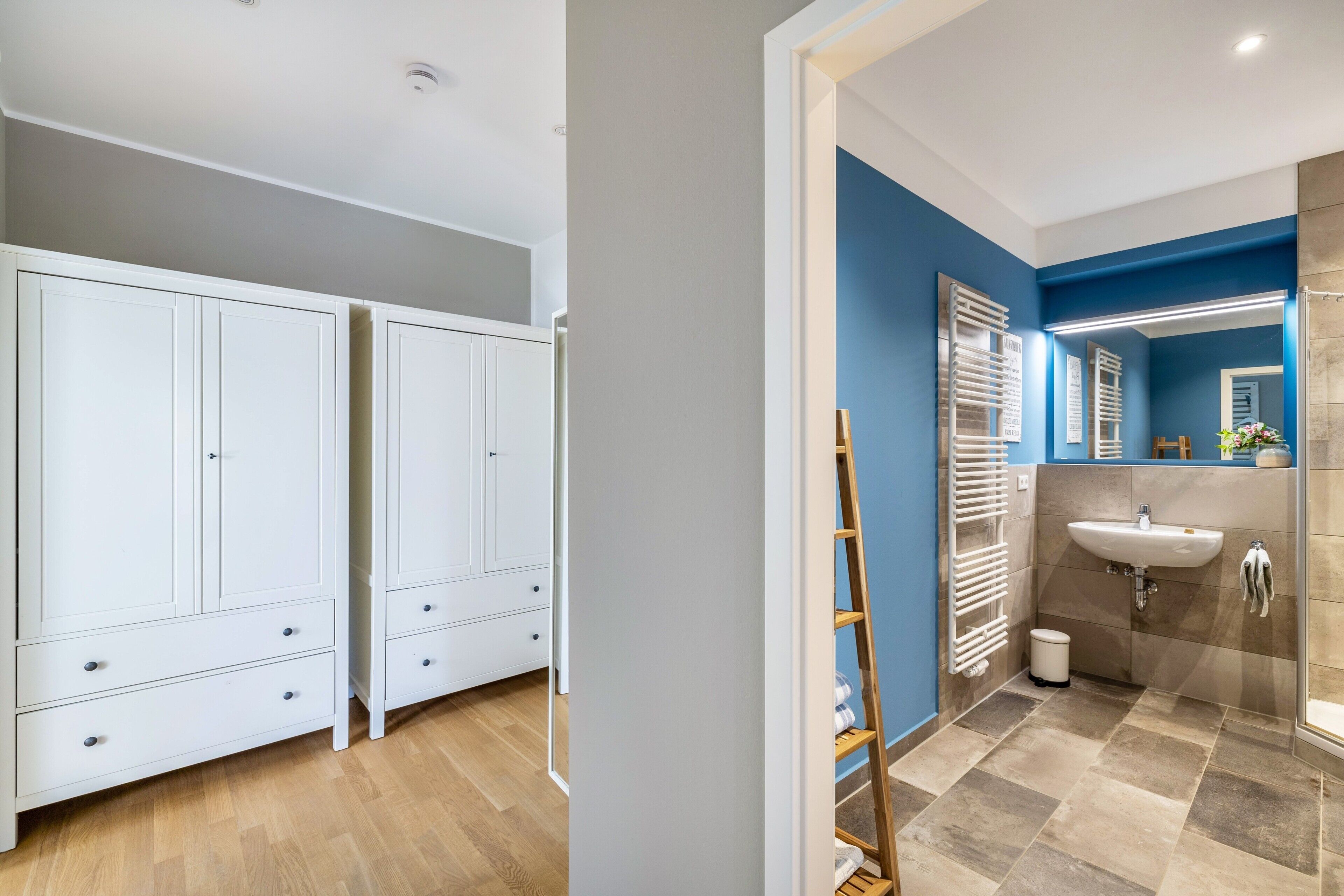 A modern bathroom with a sink, mirror, and towel rack.