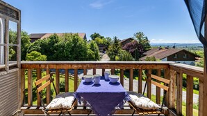 A balcony with a table set for four, overlooking a residential area with houses and trees.