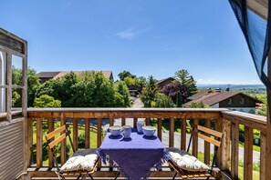 A balcony with a table set for four, overlooking a residential area with houses and trees. - Apartment 'Hof am Ammersee' with Lake View, Balcony, and Wi-Fi (Pähl)