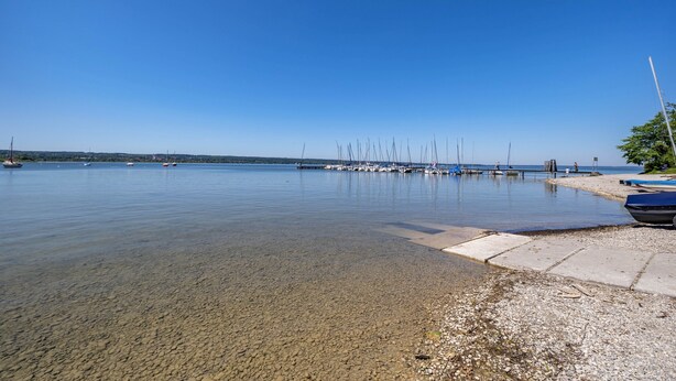 A calm lake with boats docked on the shore.