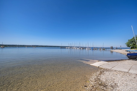 A calm lake with boats docked on the shore.. Apartment 'Hof am Ammersee' with Lake View, Balcony, and Wi-Fi