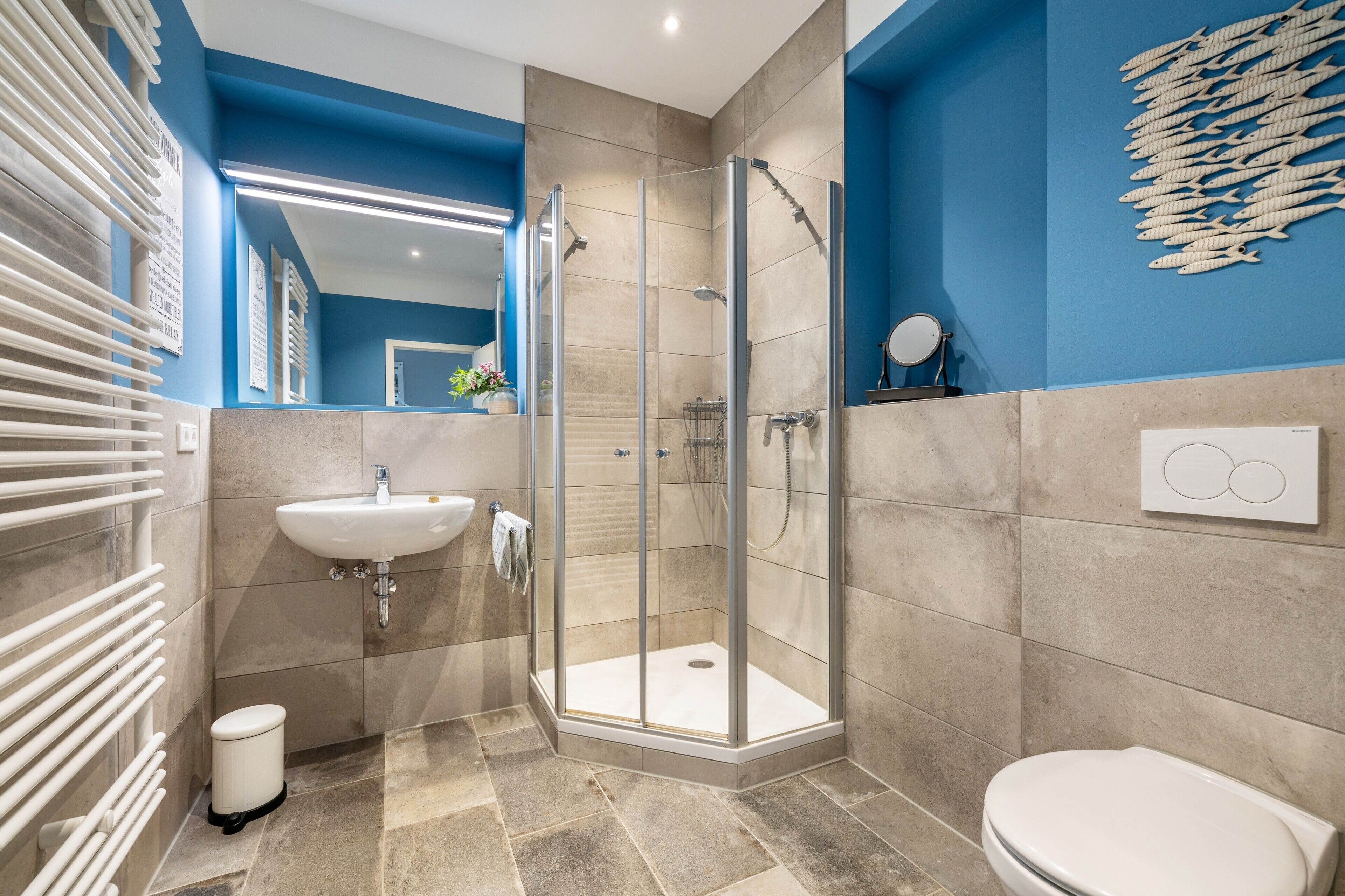 A modern bathroom with a glass shower enclosure, a sink, and a toilet.