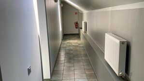 En smal hall med ett takfönster, ett element och en brandsläckare.