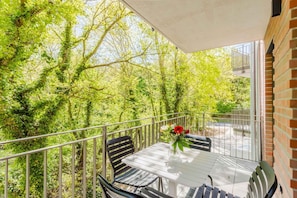 A balcony with a table and chairs, surrounded by greenery. - MEERholung apartment 1.7 close to the beach with two bedrooms and sofa bed - MEERholung (Cuxhaven)